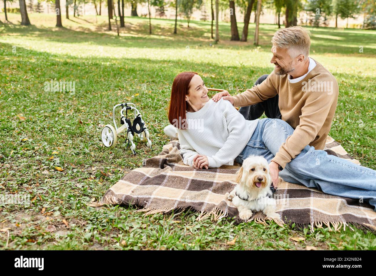 Ein Mann und eine Frau entspannen sich auf einer Decke mit ihrem Hund im Park. Stockfoto