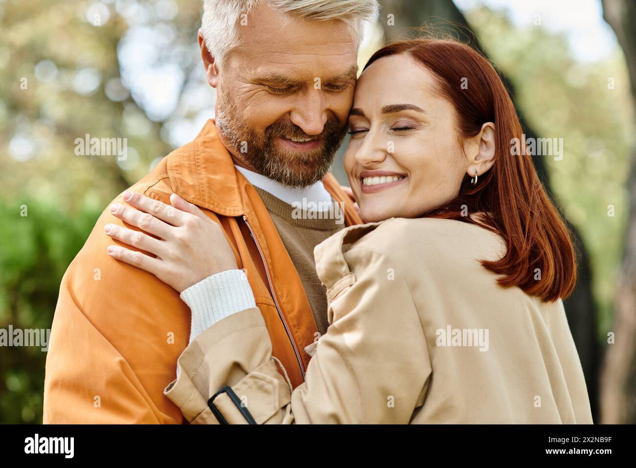 Ein Mann und eine Frau in lässiger Kleidung, die sich leidenschaftlich in einem Park umarmen. Stockfoto