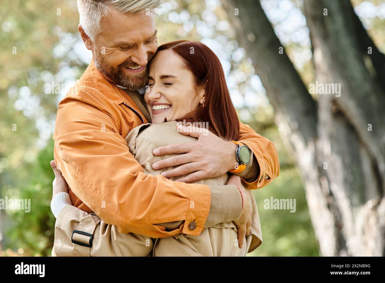 Ein Mann umarmt eine Frau zärtlich in einem Park voller üppiger Grünflächen. Stockfoto