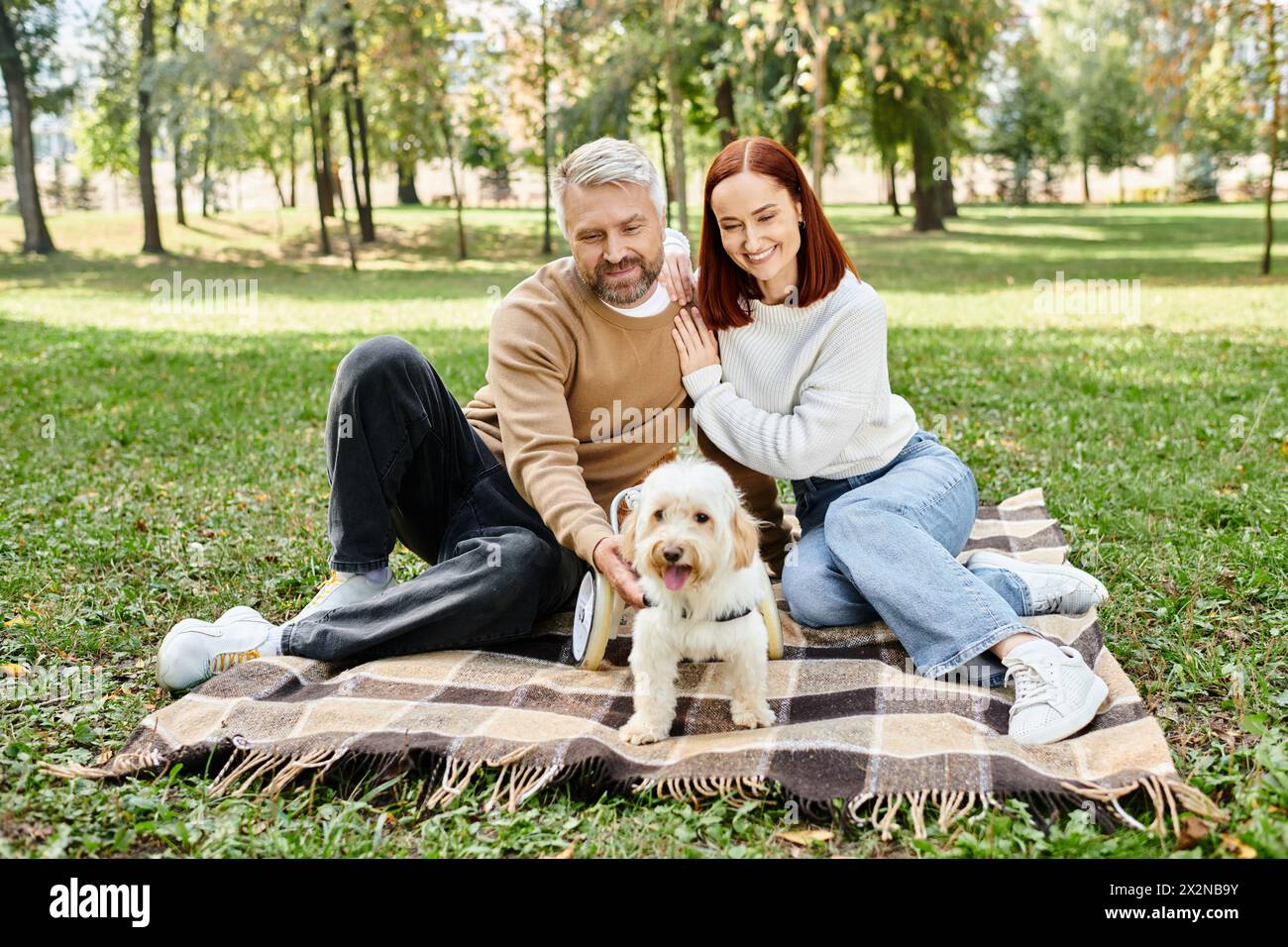 Ein Paar mit ihrem Hund entspannt sich auf einer Decke im Park. Stockfoto