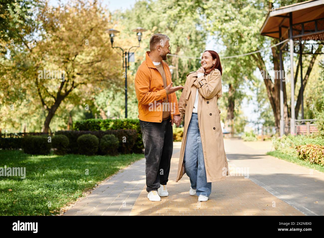 Ein Mann und eine Frau in lässiger Kleidung, die einen Bürgersteig in einem Park hinunterlaufen. Stockfoto