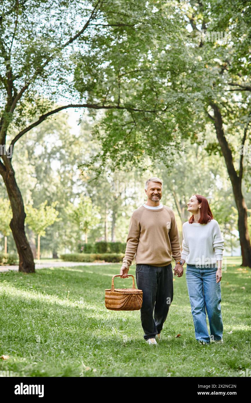 Ein Mann und eine Frau, die einen romantischen Spaziergang durch einen Park genießen und Hände halten. Stockfoto