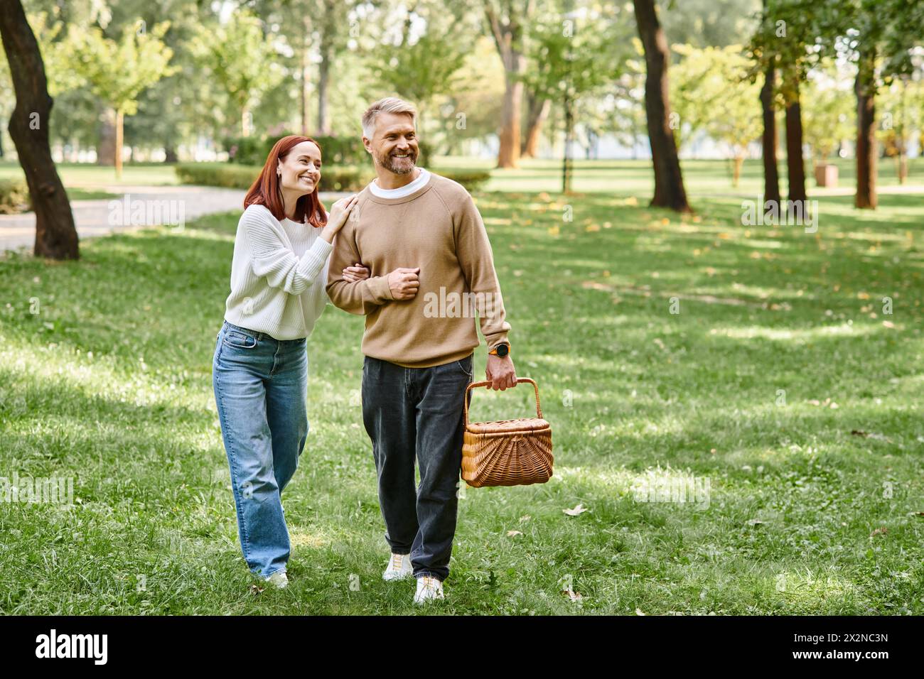 Ein Mann und eine Frau in lässiger Kleidung gehen friedlich durch einen Park. Stockfoto