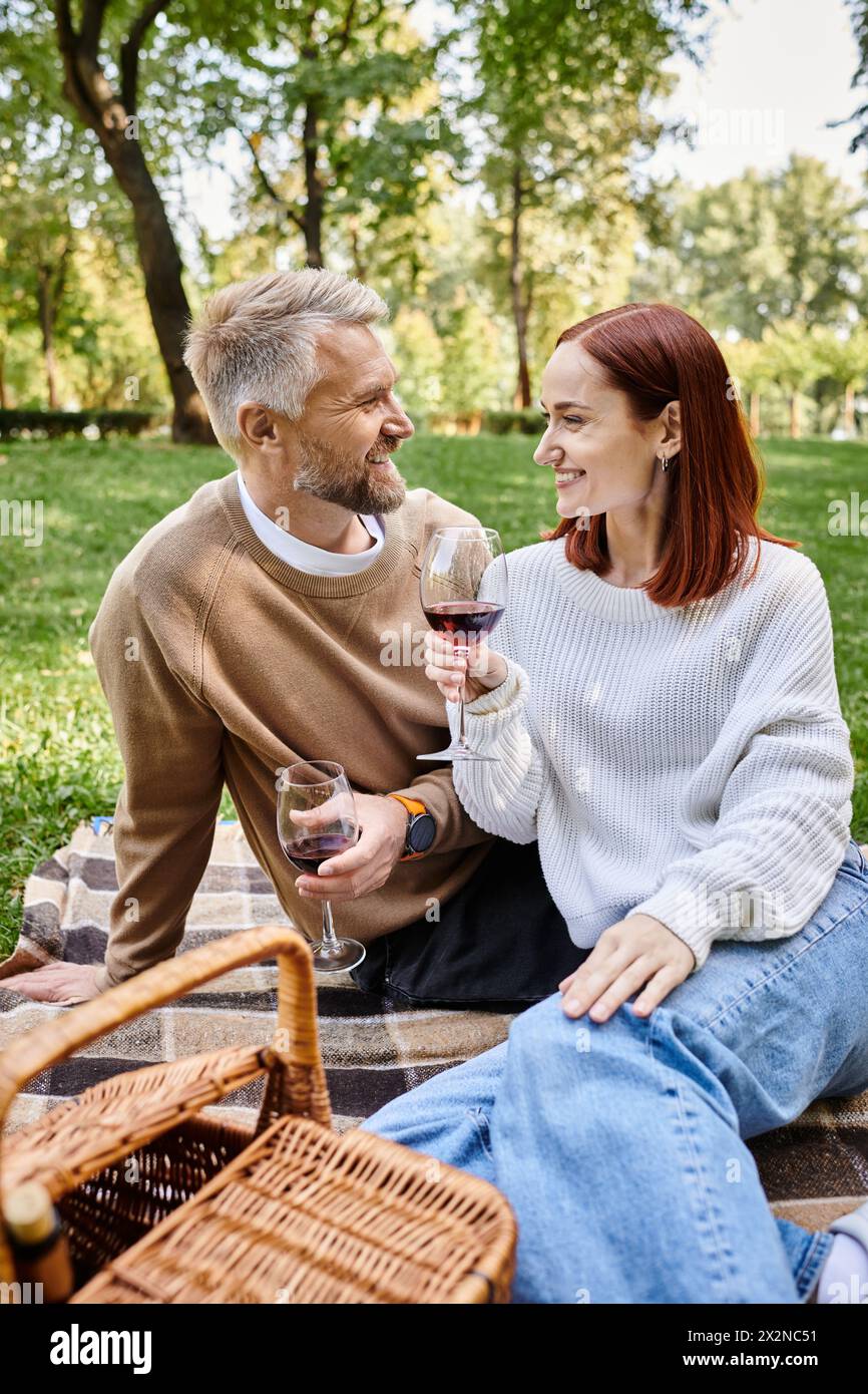 Mann und Frau genießen Wein auf einer Decke im Park. Stockfoto
