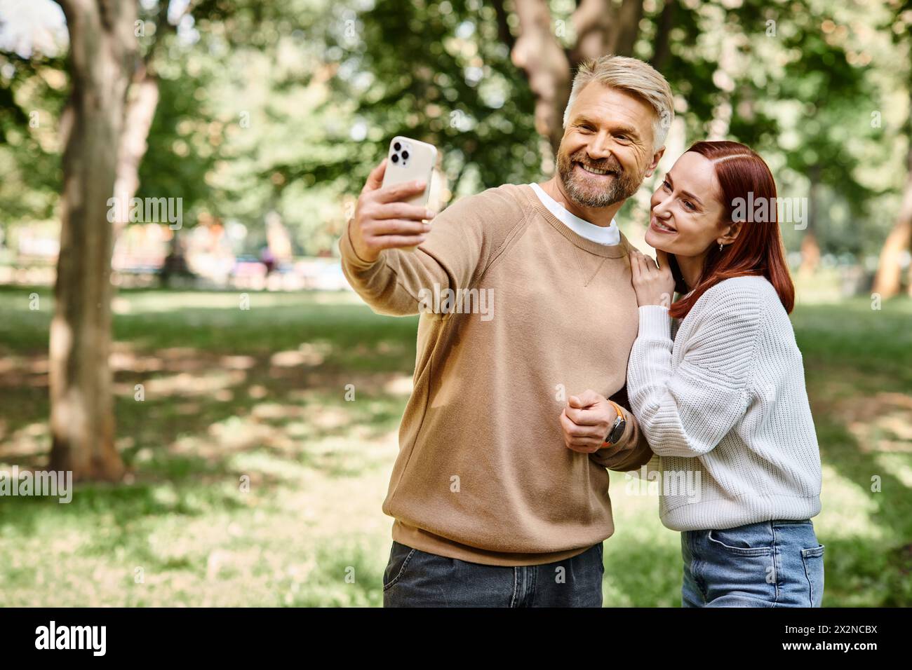 Ein Mann und eine Frau fangen einen Moment zusammen in einem Park ein, indem sie ein Selfie machen. Stockfoto