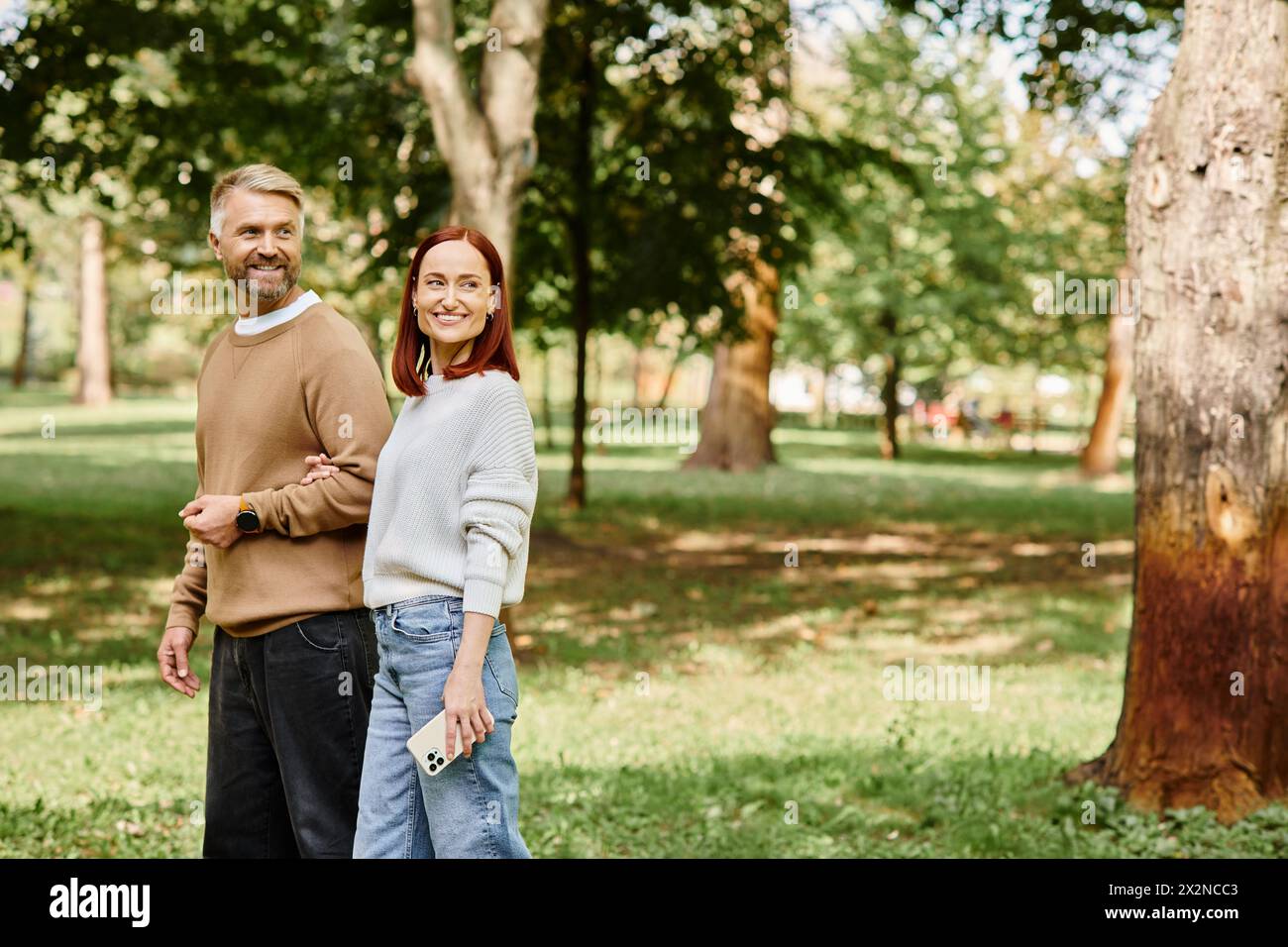 Ein Mann und eine Frau in lässiger Kleidung stehen nebeneinander in einem üppigen Park. Stockfoto