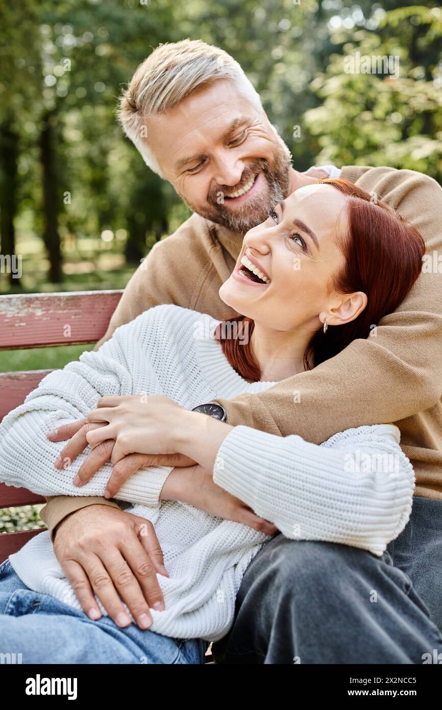 Ein Mann und eine Frau in lässiger Kleidung sitzen friedlich auf einer Bank im Park. Stockfoto