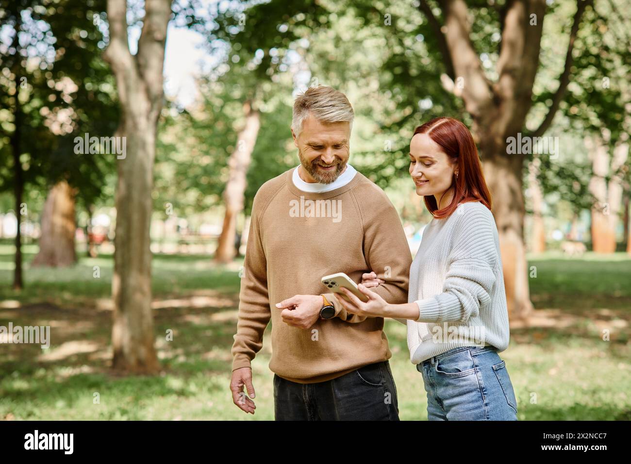 Ein Mann und eine Frau in lässiger Kleidung, die in einem friedlichen Park spazieren gehen. Stockfoto