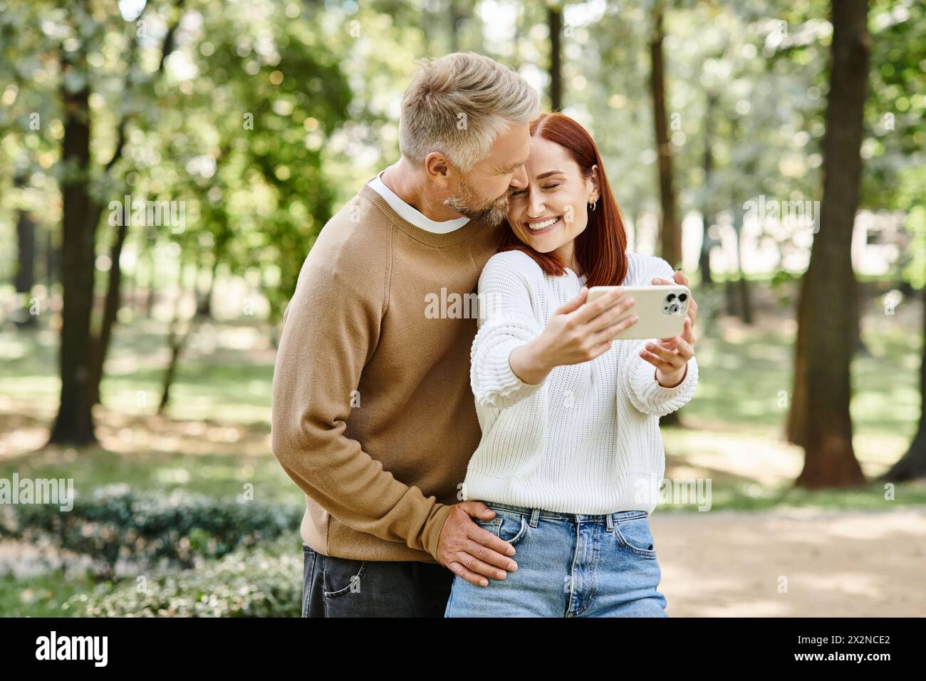 Ein Mann und eine Frau in lässiger Kleidung, die mit einem Handy verlobt sind. Stockfoto