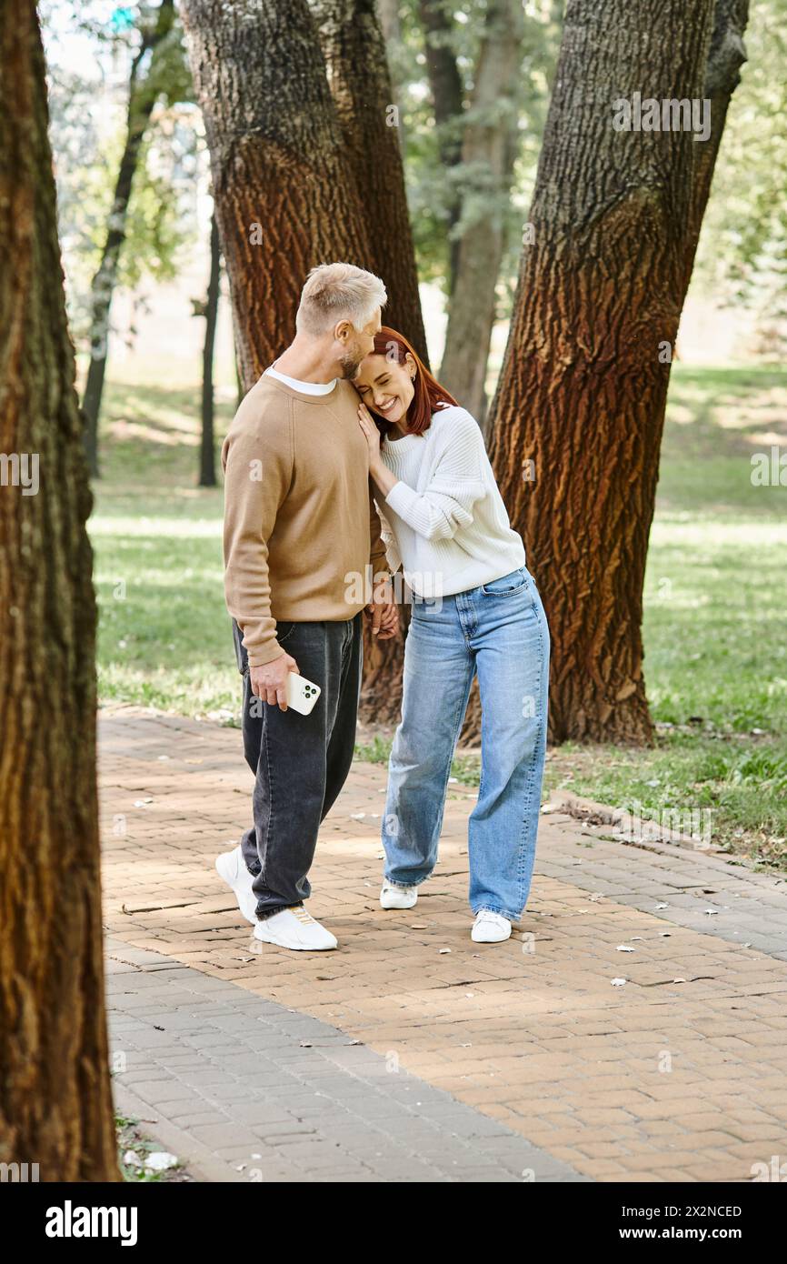 Ein Mann und eine Frau in lässiger Kleidung stehen zusammen in einem Park, umgeben von der Natur. Stockfoto