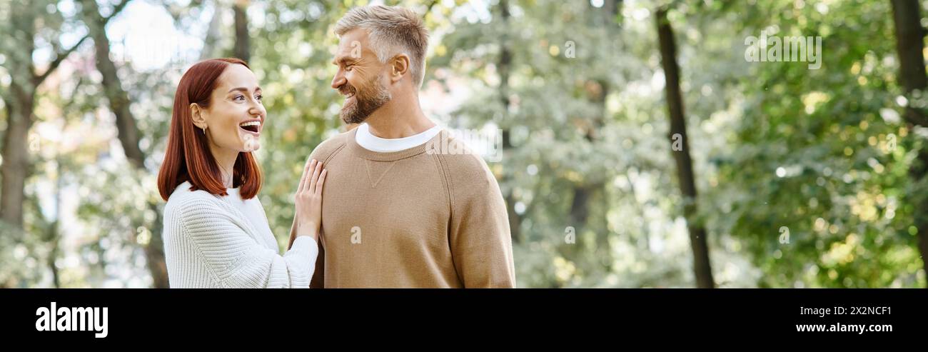 Ein Mann und eine Frau in lässiger Kleidung stehen zusammen im Wald. Stockfoto