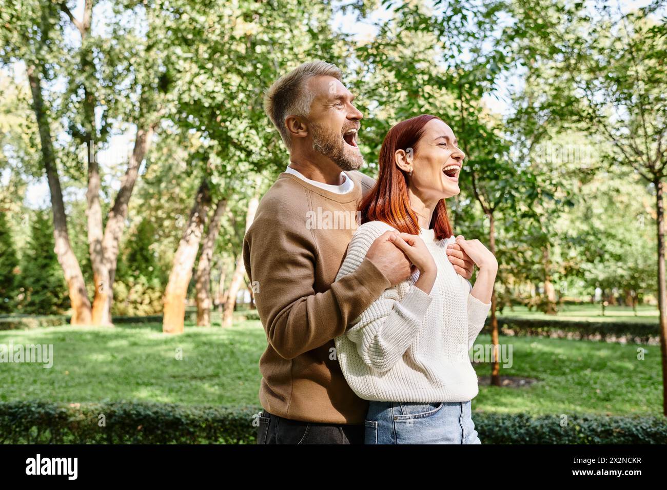 Ein Mann und eine Frau lachen zusammen in einem Park. Stockfoto