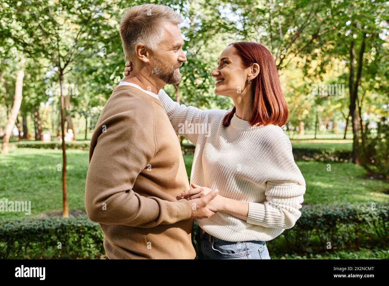 Ein Mann und eine Frau, ein liebevolles Paar, stehen zusammen in einem friedlichen Park. Stockfoto