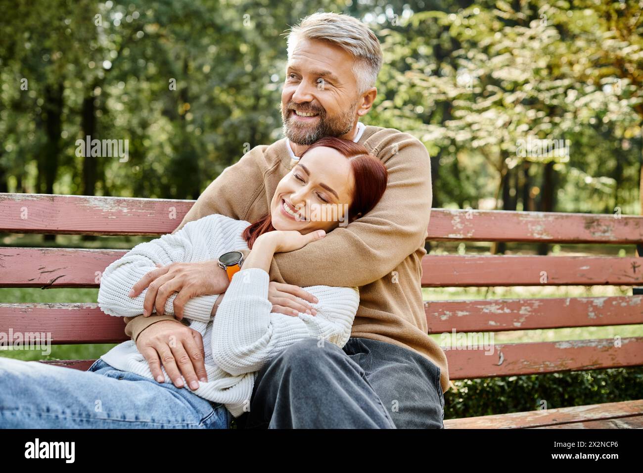 Ein Mann und eine Frau sitzen auf einer Bank in einem friedlichen Park. Stockfoto