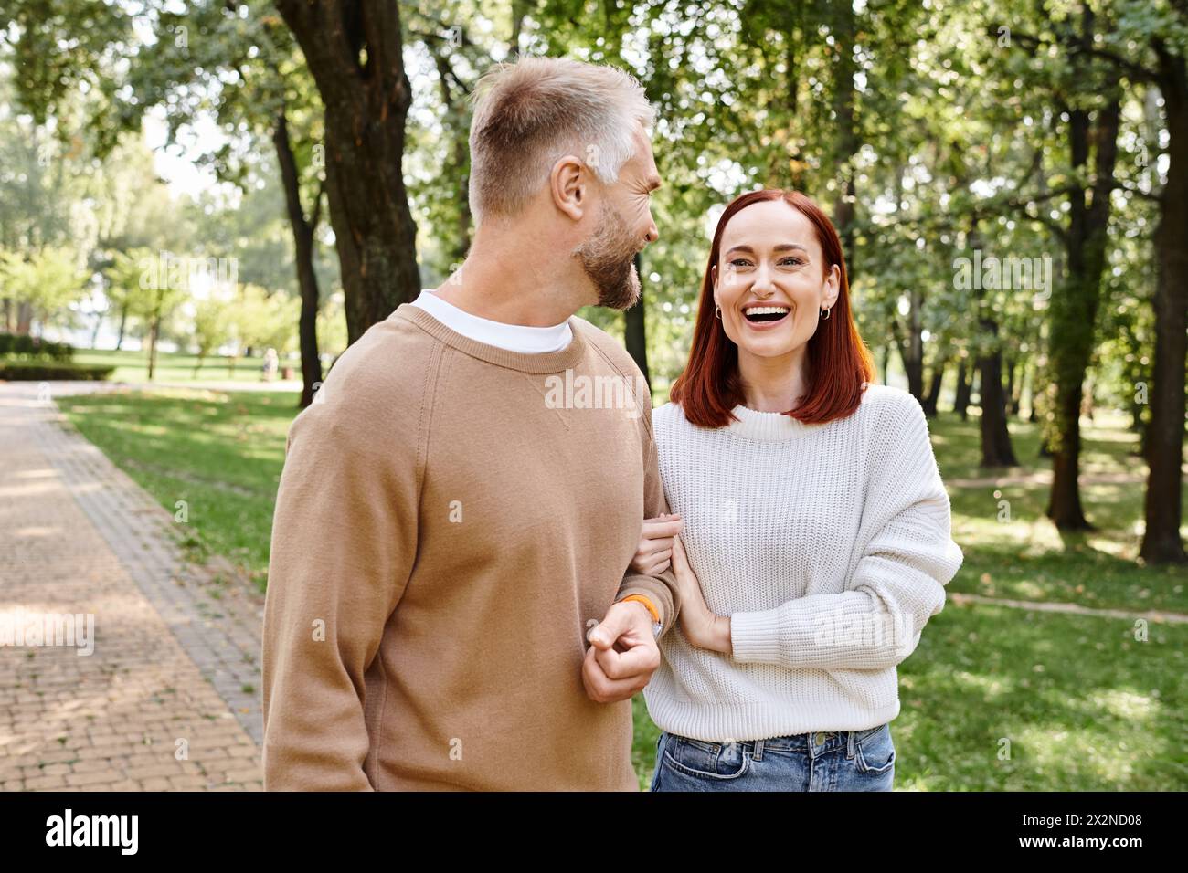 Ein Mann und eine Frau in lässiger Kleidung spazieren durch einen üppigen Park. Stockfoto