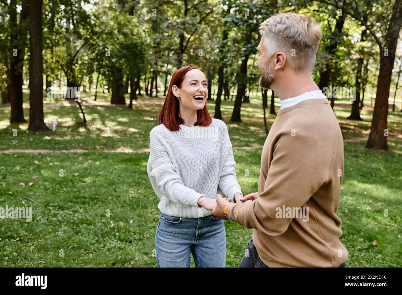 Ein Mann und eine Frau, die bei einem Spaziergang durch den Park Hände halten. Stockfoto