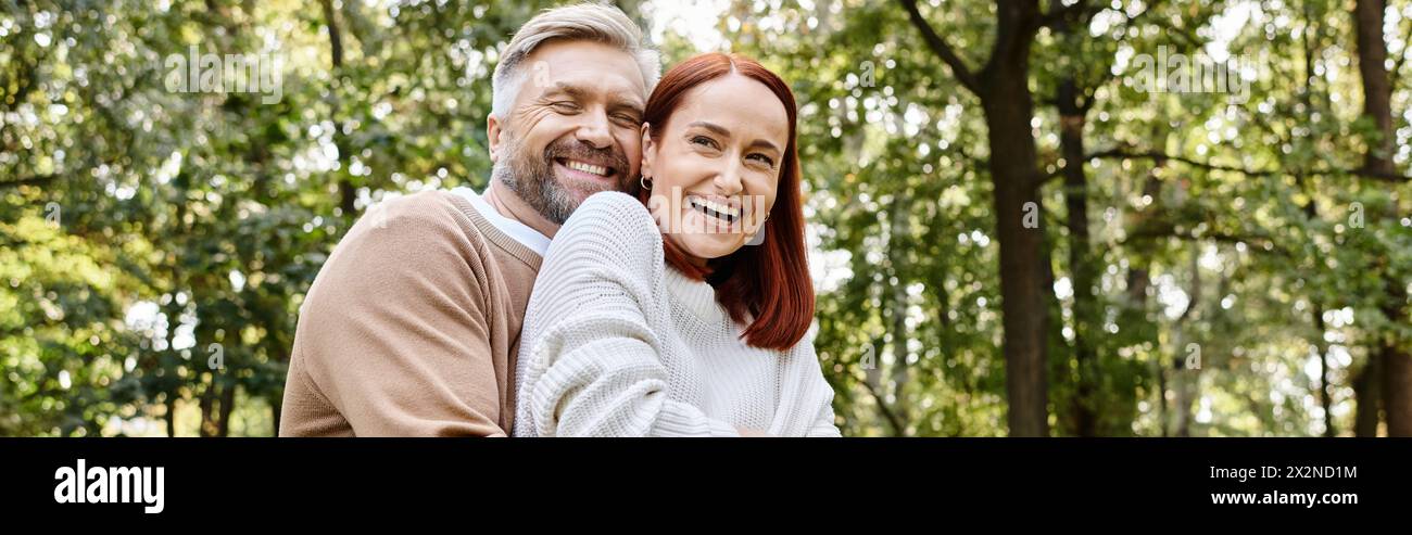 Ein Mann und eine Frau im Wald, die liebevoll auf einem Spaziergang lächeln. Stockfoto