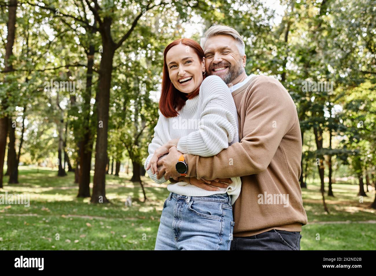 Ein Mann und eine Frau teilen eine warme Umarmung in der ruhigen Umgebung eines Parks. Stockfoto