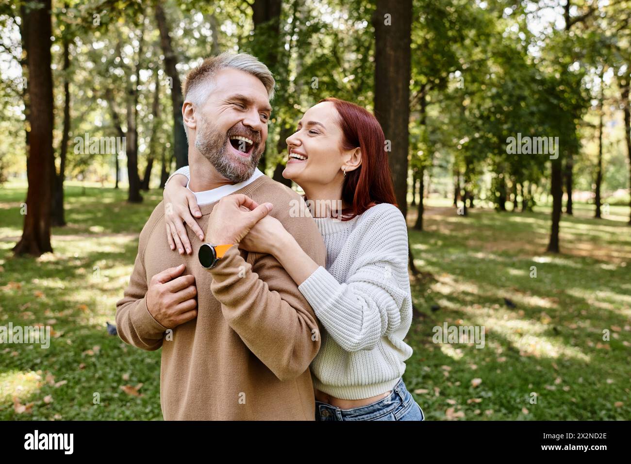 Ein Mann hält eine Frau zärtlich in einem Park. Stockfoto