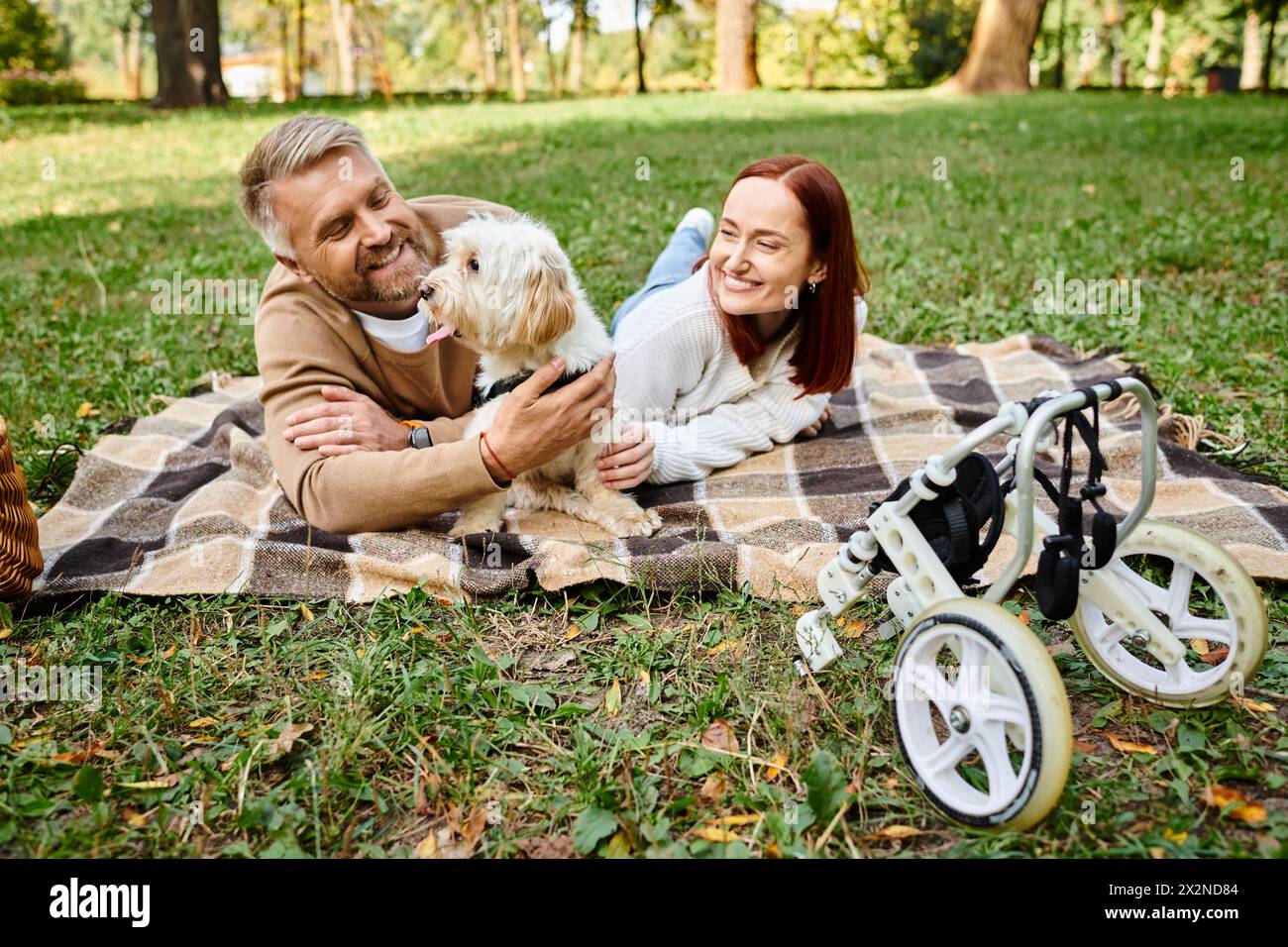 Ein Mann und eine Frau in lässiger Kleidung liegen mit ihrem Hund auf einer gemütlichen Decke im Park. Stockfoto