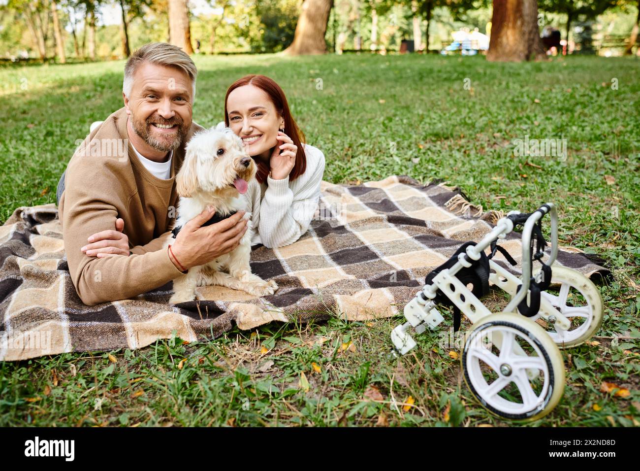 Ein Mann und eine Frau, die sich auf einer Decke mit ihrem Hund im Park entspannen. Stockfoto