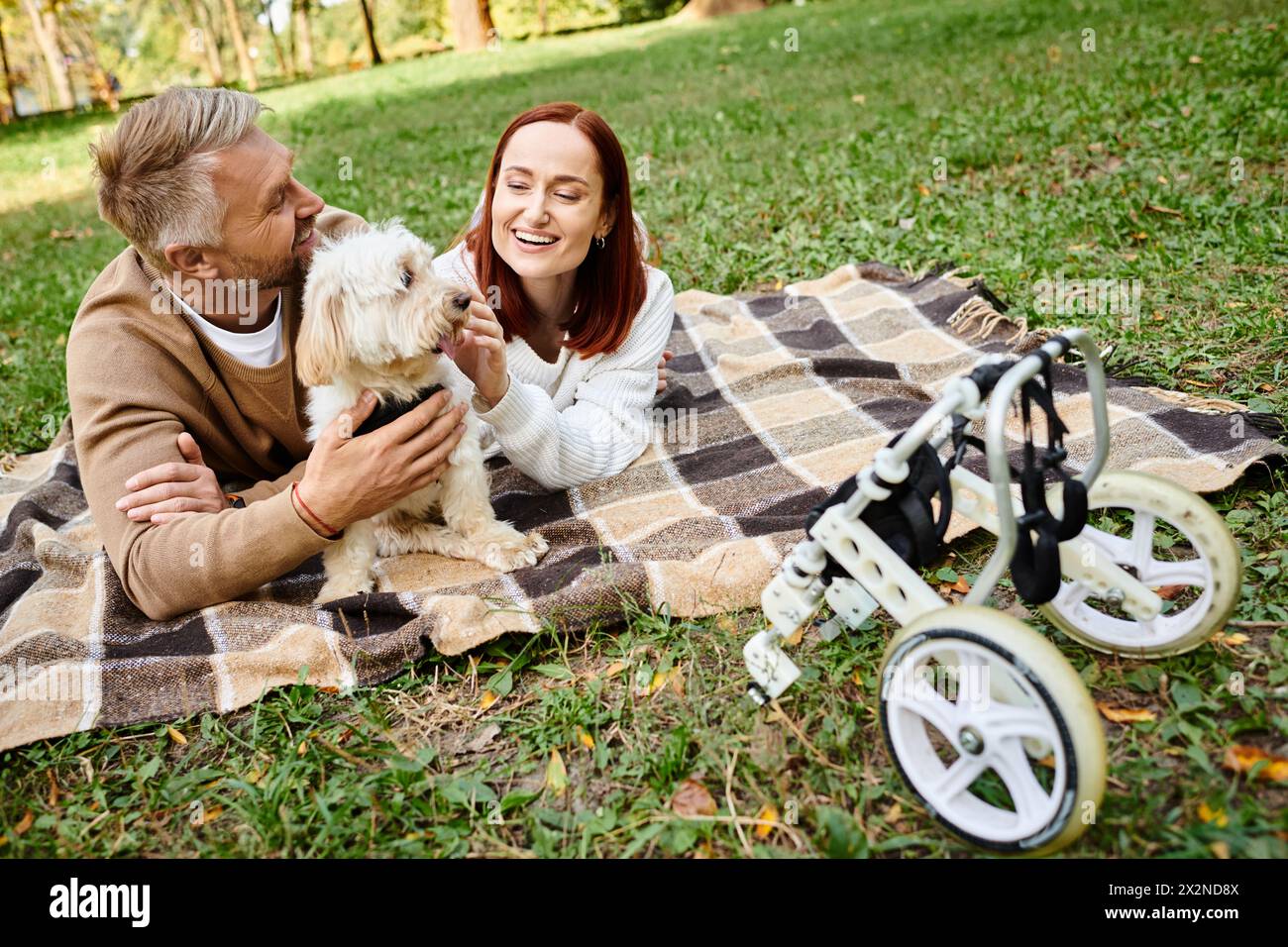 Ein Mann und eine Frau lagen mit ihrem Hund in einem Park auf einer Decke. Stockfoto