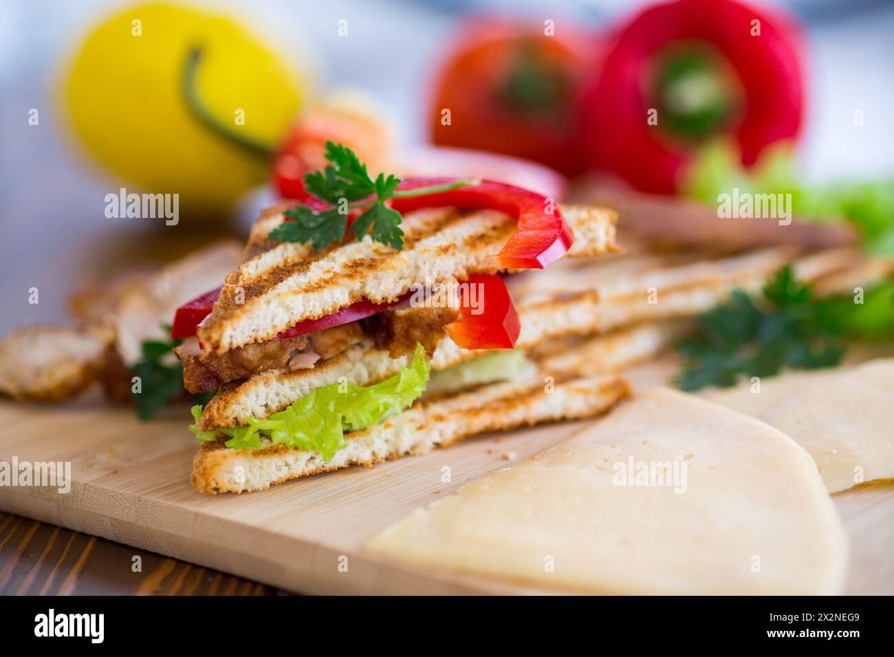 Gebratener Toast mit Huhn, Salat, Gemüse auf einem Holztisch. Stockfoto