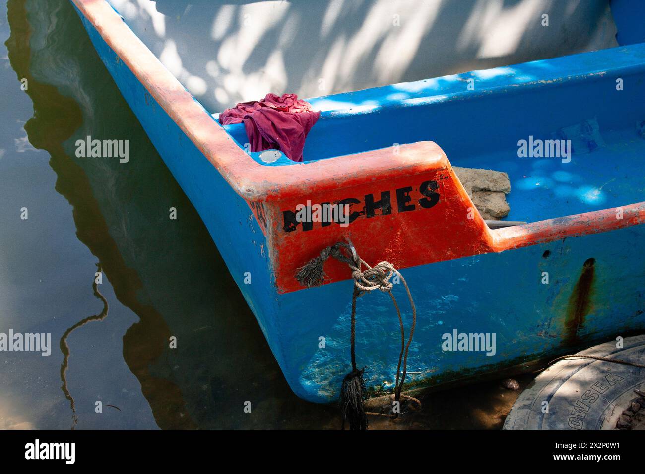 Bote colorido que reposa apaciblemente en la pintoresca orilla del Río en Miches, República Dominicana. Stockfoto