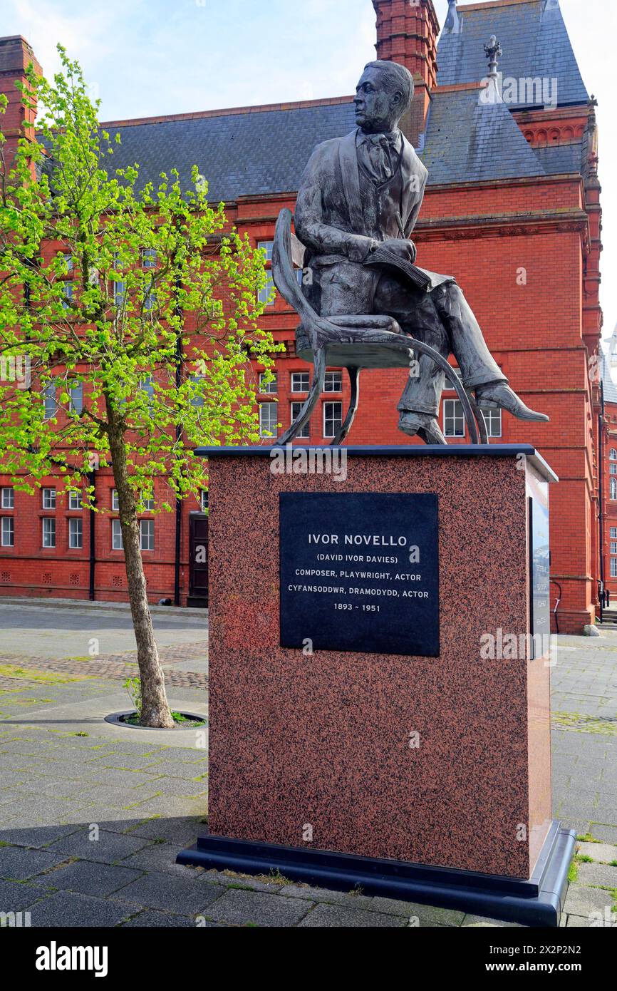 Ivor Novello Bronzestatue auf erhöhtem Sockel mit dem roten Backsteinhaus Pierhead im Hintergrund. Cardiff Bay, Aufgenommen Im April 2024 Stockfoto