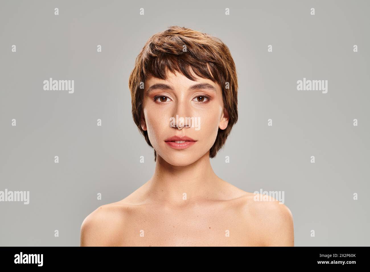 Eine Nahaufnahme einer Person mit kurzen Haaren, die vor einem lebendigen Hintergrund posiert. Stockfoto