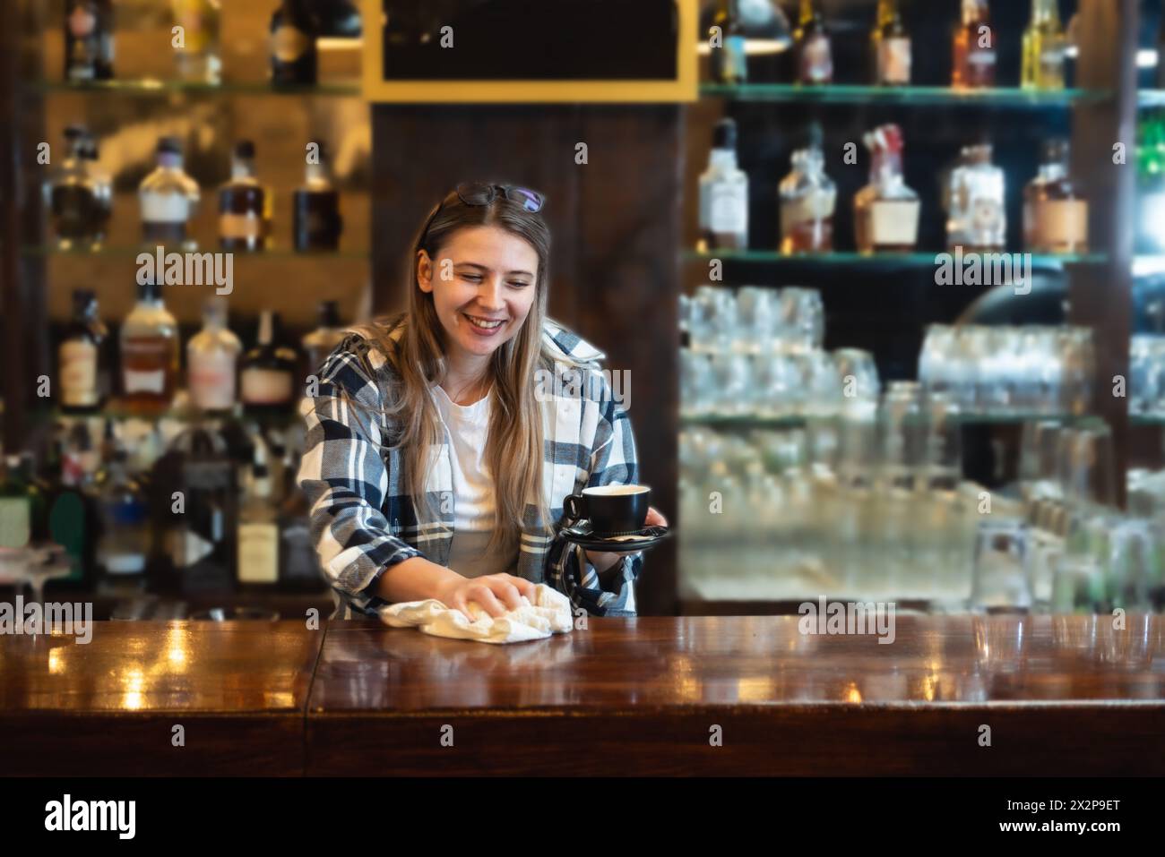 Die Kellnerin stand in der Bar und wischte und polierte das Bierglas. Die Barkeeperin arbeitet an der Bar, bereitet und putzt, arbeitet, bevor Gäste kommen, Stockfoto
