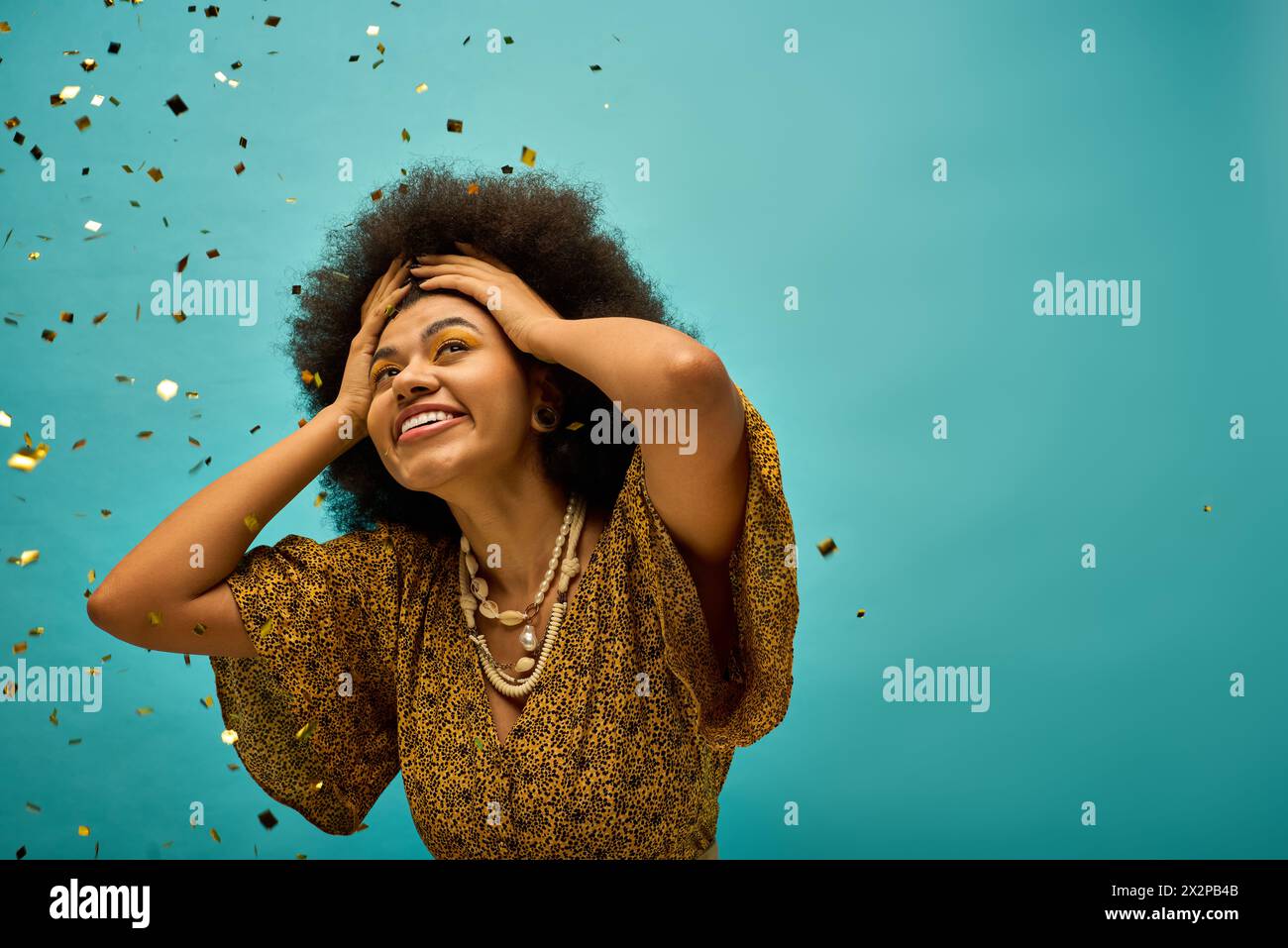 Afroamerikanerin in einem goldenen Kleid, die inmitten von Konfetti steht. Stockfoto