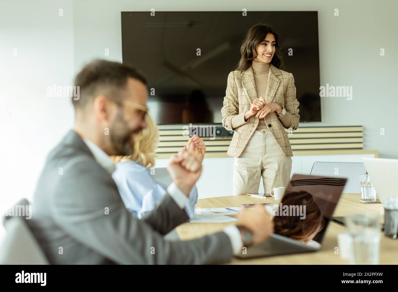 Die kompetente Frau präsentiert sich während eines Meetings vor Kollegen, wobei ihr Ausdruck Begeisterung und Führungsstärke zum Ausdruck bringt Stockfoto