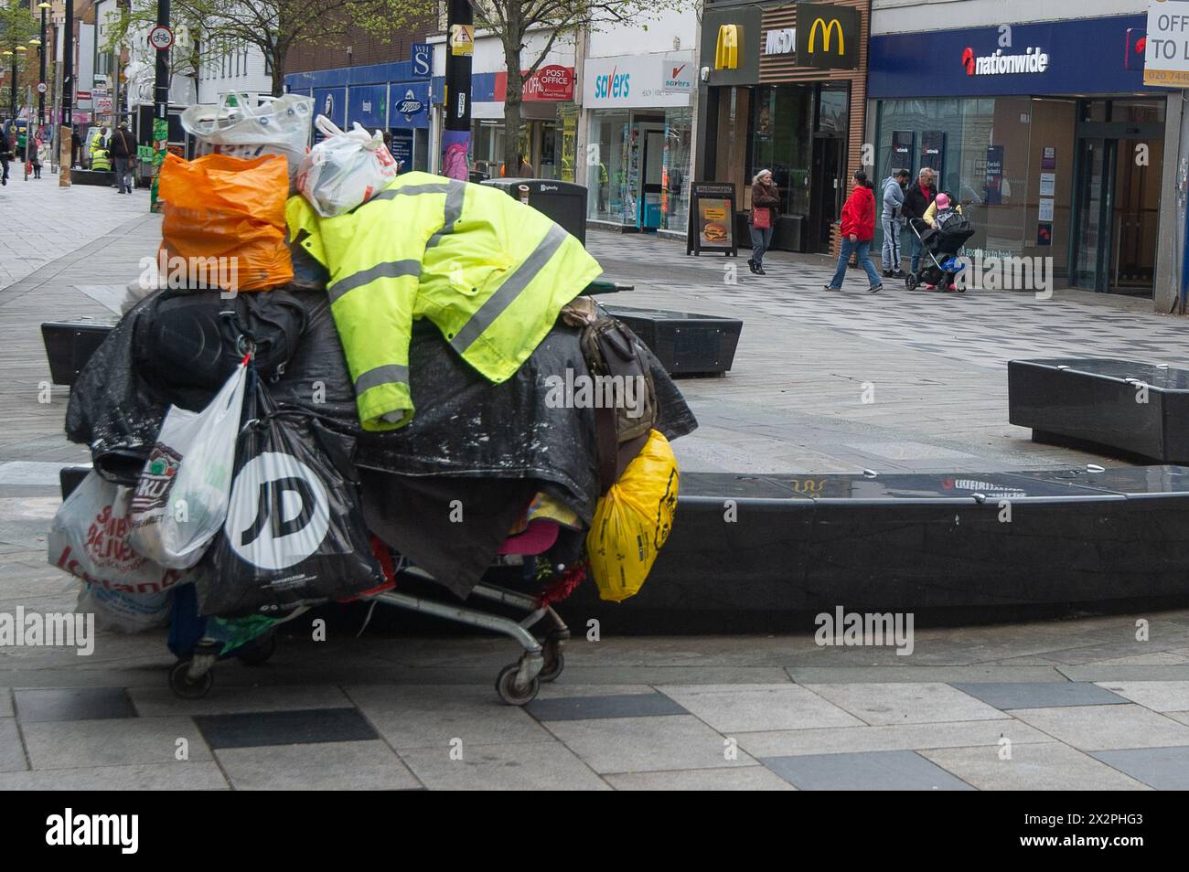 Slough, Berkshire, Großbritannien. April 2024. Der tragische Anblick eines Obdachlosen aus Osteuropa, mit all seinen weltlichen Besitztümern, die in Plastiktüten von einem Einkaufswagen in der Slough High Street hängen. Das neue Gesetz über Strafrechtspflege wird derzeit vom Parlament durchlaufen und würde es der Polizei ermöglichen, „belästigende“ Schläfer mit Geldbußen zu belegen. Das Gesetz würde bedeuten, dass raue Schläfer weitergezogen werden könnten, mit einer Geldstrafe von bis zu 2.500 Pfund belegt oder inhaftiert werden könnten. Quelle: Maureen McLean/Alamy Live News Stockfoto