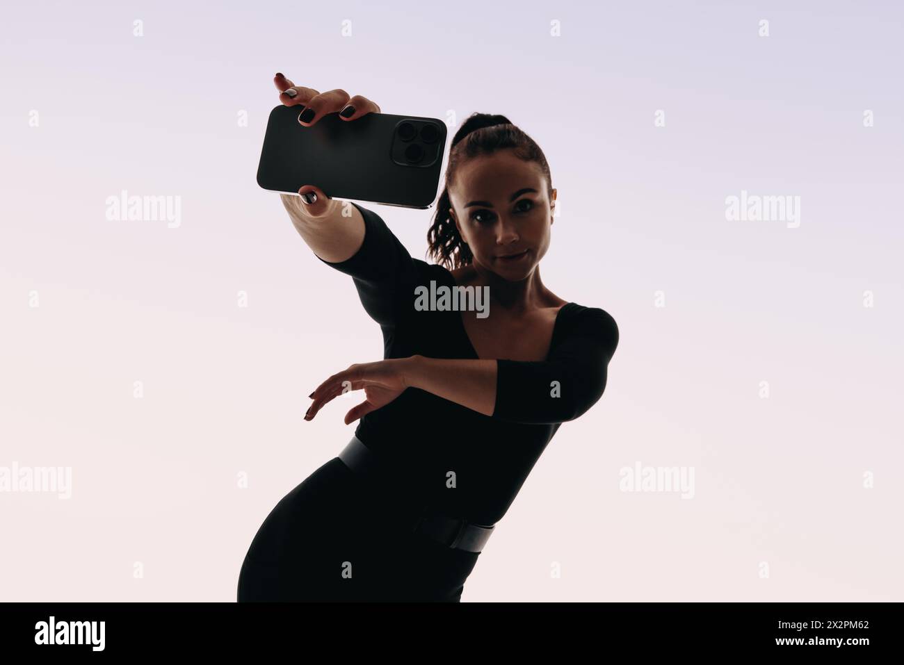 Selbstbewusste Tänzerin in einem Studio, die mit ihrem Smartphone ein lustiges und dynamisches Selfie-Video aufnimmt. Selbstvertrauen ausdrücken und Technologie annehmen Stockfoto
