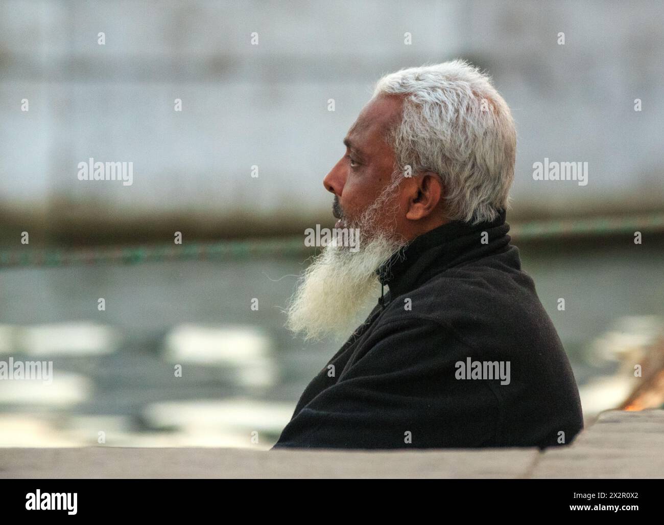 Ein älterer Mann sitzt ruhig am Ganges in Varanasi, Indien Stockfoto