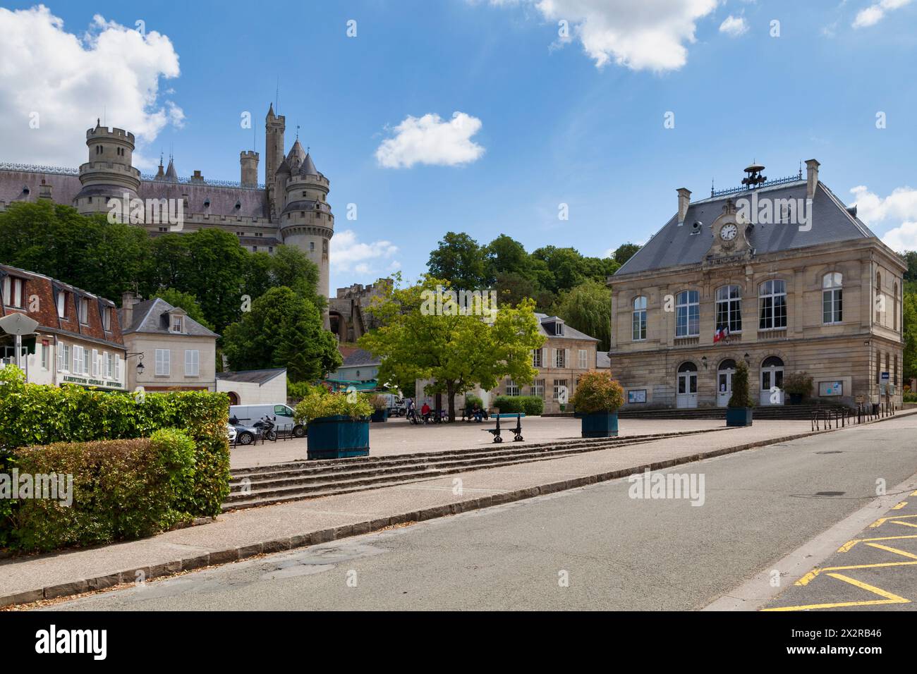 Pierrefonds, Frankreich – 25. Mai 2020: Der Place de l’Hôtel de ville mit dem Rathaus und dem Pierrefonds Castle überragt ihn. Stockfoto