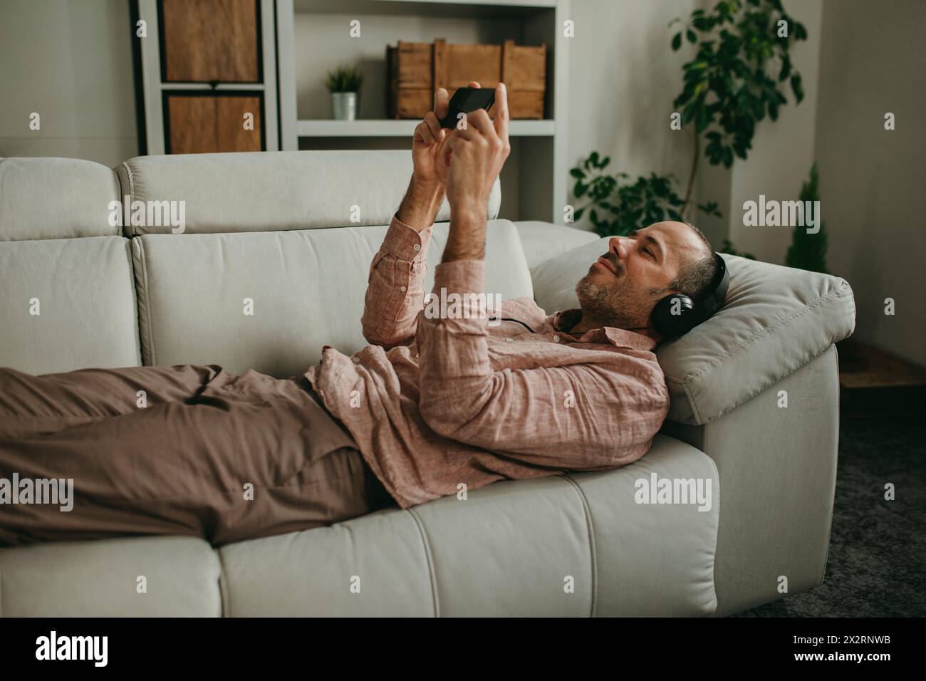 Mann, der sich zu Hause liegend und auf dem Smartphone Filme ansieht Stockfoto