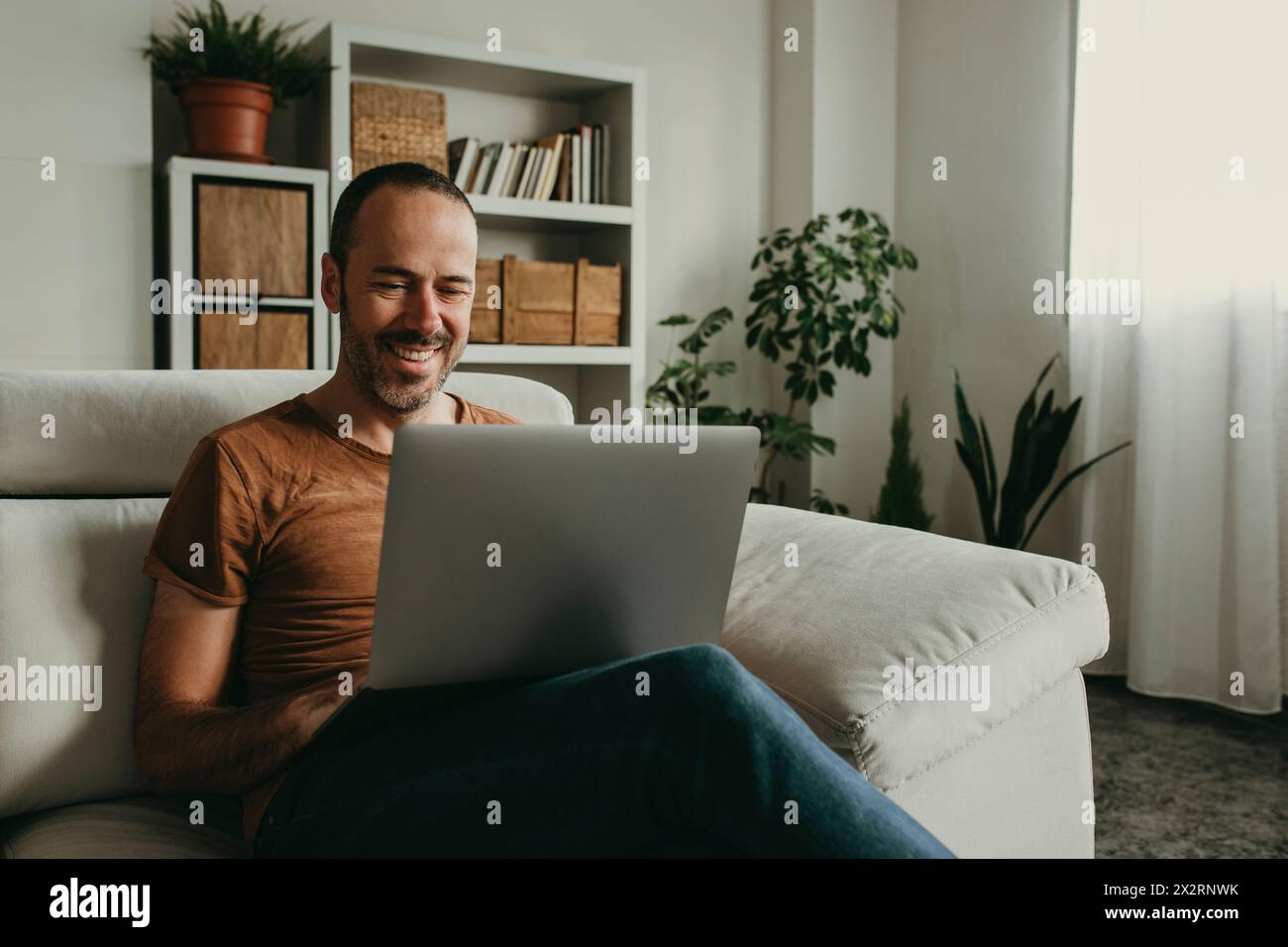 Glücklicher Mann, der zu Hause auf einem Laptop Filme ansieht Stockfoto