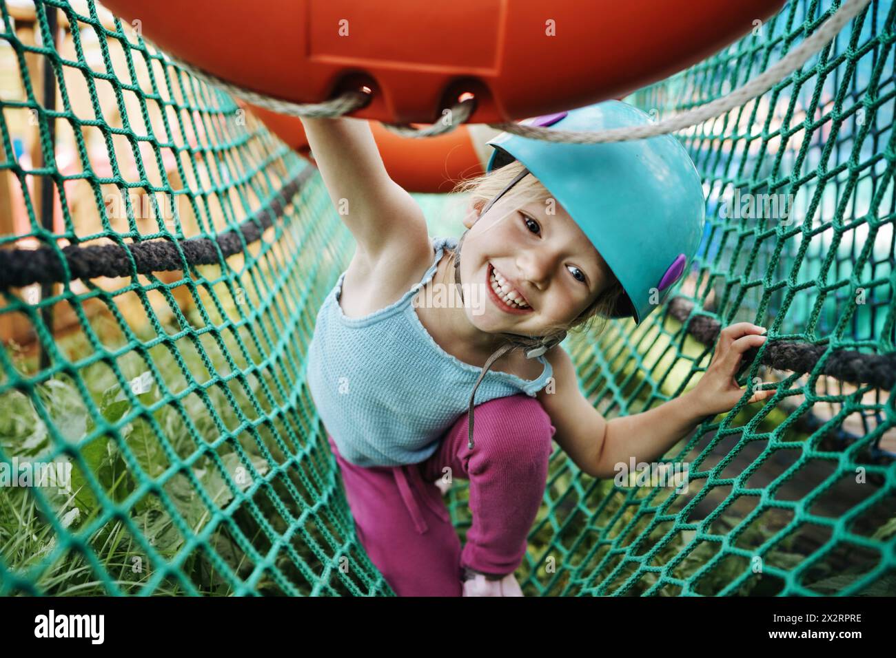 Glückliches Mädchen, das Spaß beim Spielen im Seilpark hat Stockfoto