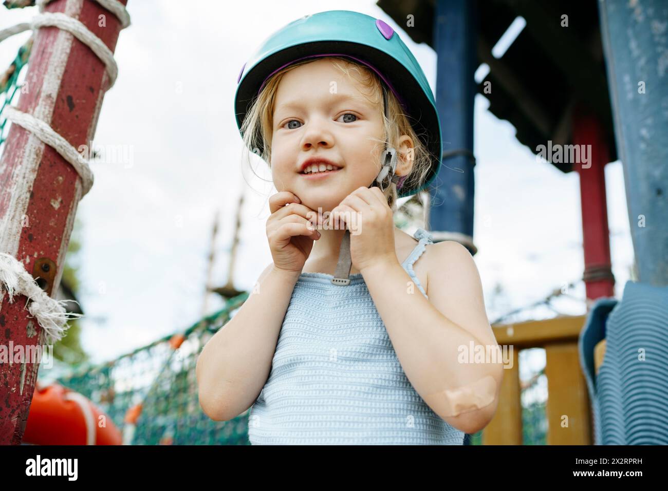 Ein lächelndes Mädchen, das im Seilpark einen Sporthelm befestigt Stockfoto