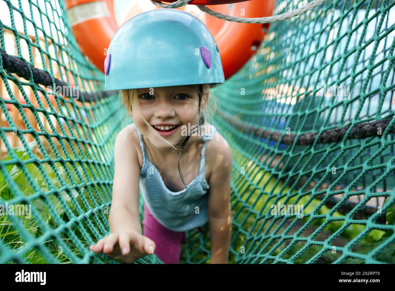 Lächelndes Mädchen, das im Netz im Abenteuerpark krabbelt Stockfoto