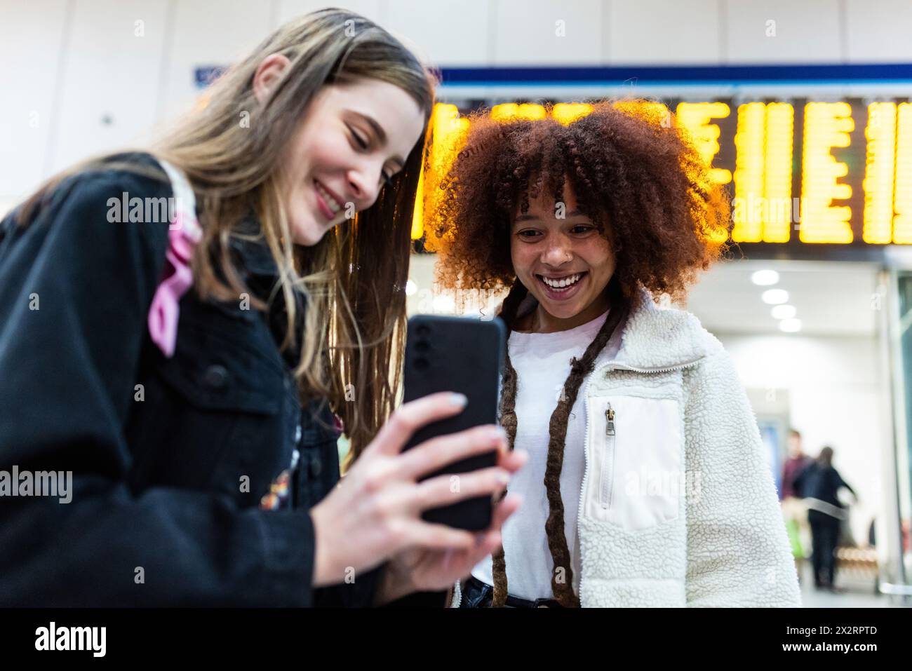 Lächelnde Frau, die dem Freund am Bahnhof das Smartphone zeigt Stockfoto