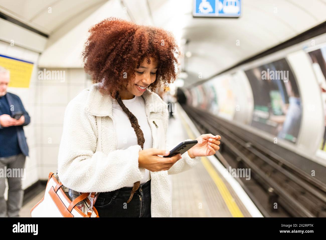 Lächelnde Frau mit Handy in der U-Bahn Stockfoto