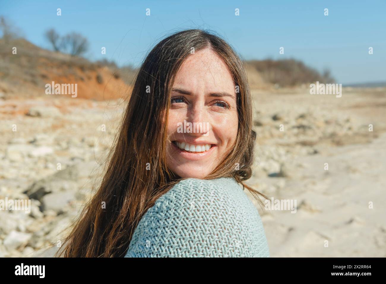 Lächelnde langhaarige Frau am sonnigen Tag Stockfoto