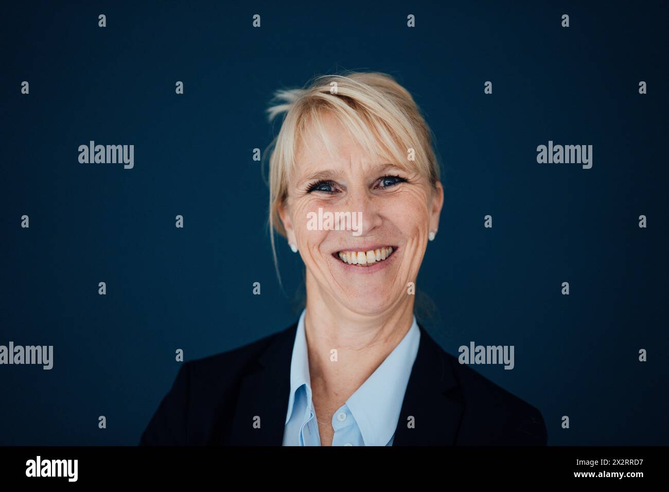 Glückliche Geschäftsfrau vor marineblauem Hintergrund Stockfoto