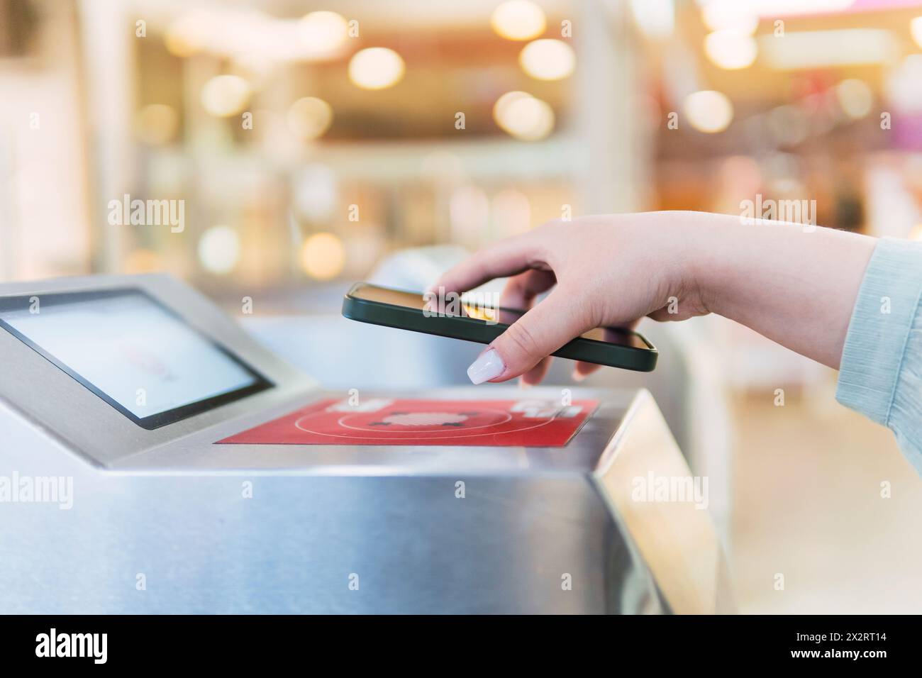 Die Hand einer Frau scannt QR-Code durch das Smartphone am Drehkreuz Stockfoto