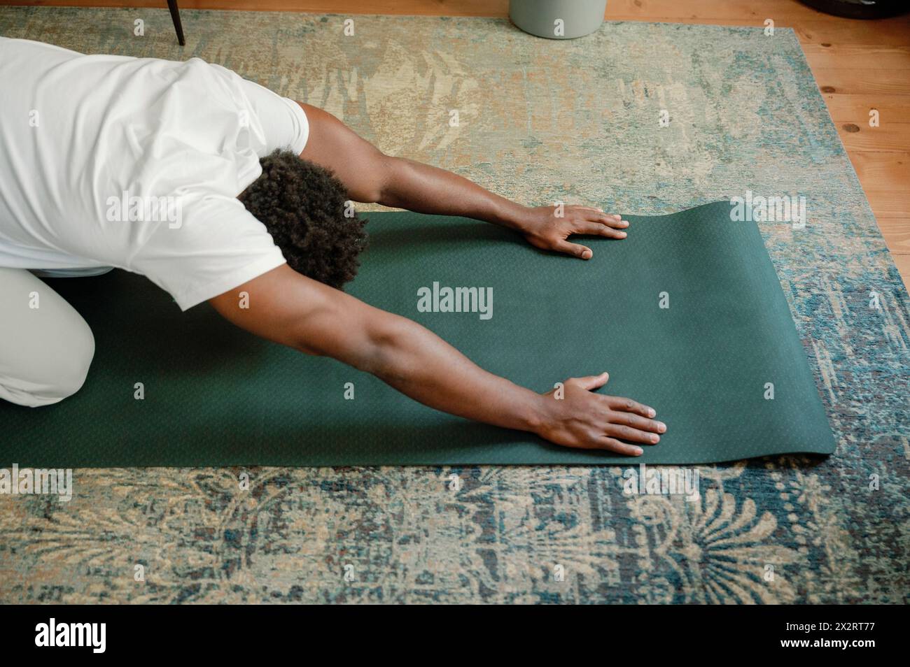 Mann, der sich auf der Trainingsmatte ausdehnt und zu Hause Yoga macht Stockfoto