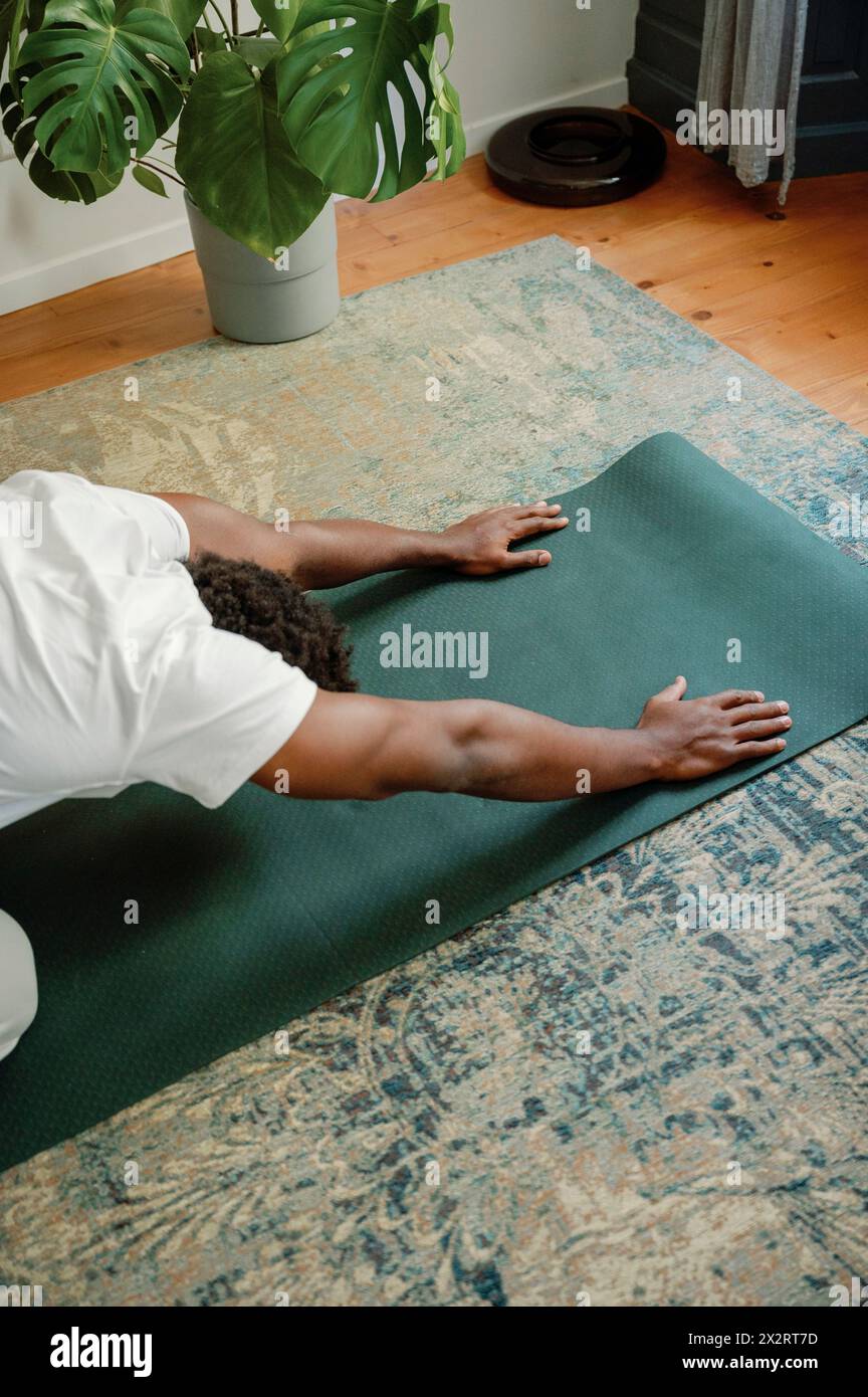 Mann dehnt sich auf der Trainingsmatte aus und macht morgens Yoga zu Hause Stockfoto