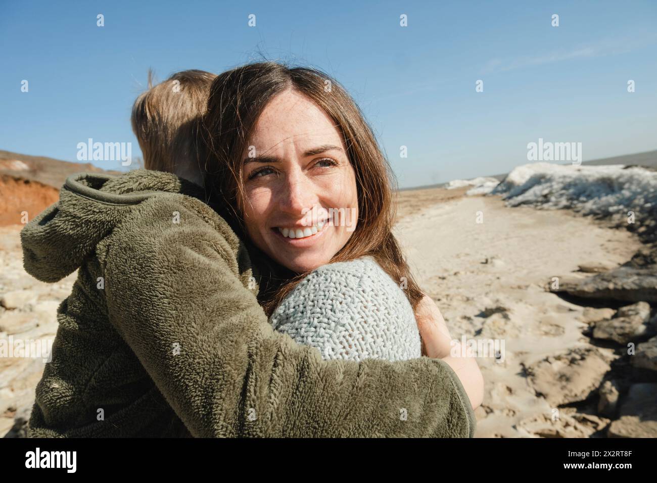 Glückliche Mutter und Sohn, die sich an sonnigen Tagen umarmen Stockfoto